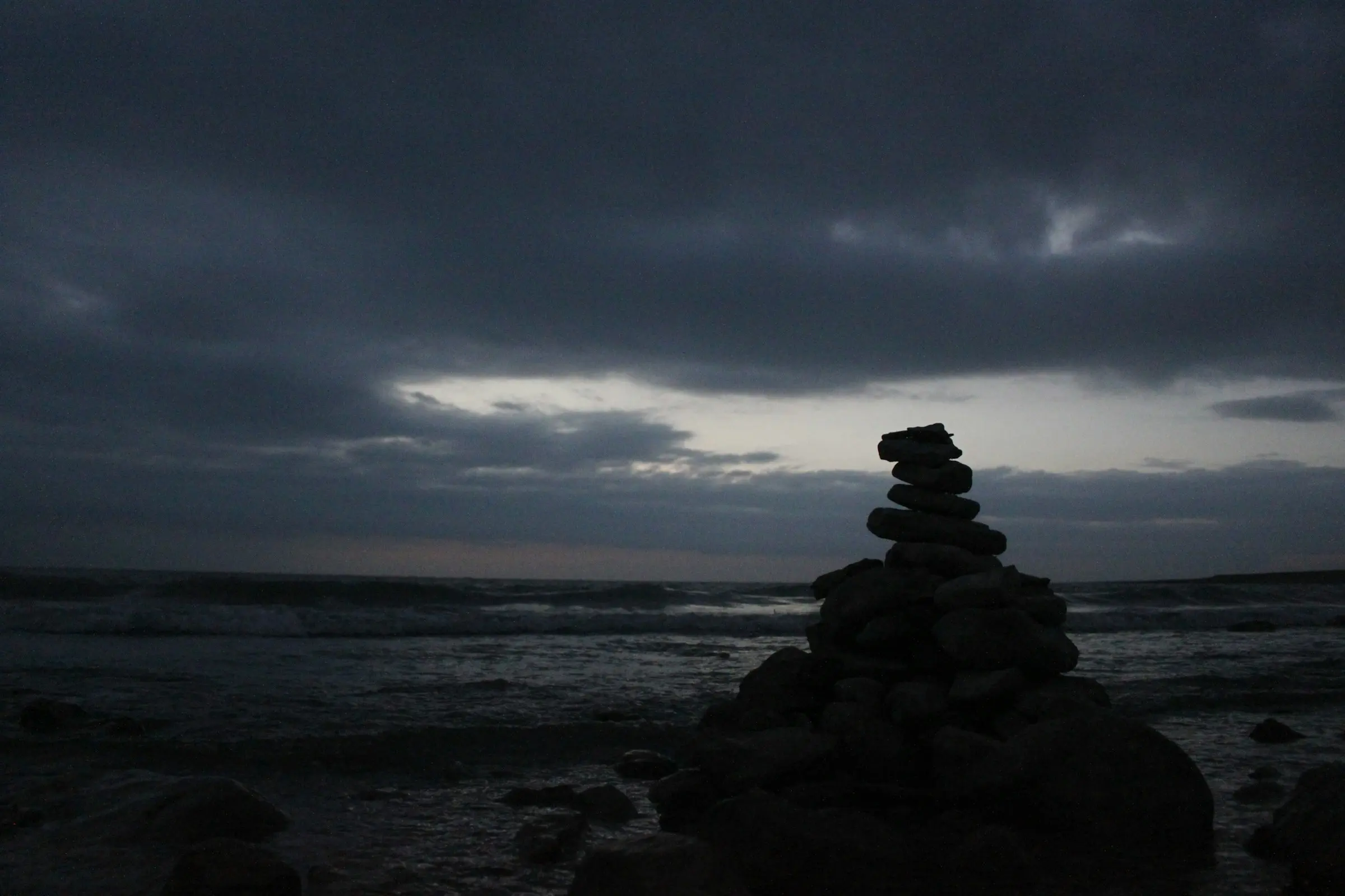 Stacked stones by still water at dusk